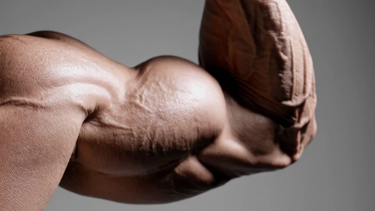 Primo piano di un fermo immagine video di un braccio muscoloso e flesso, che mette in risalto la texture dettagliata e la definizione.