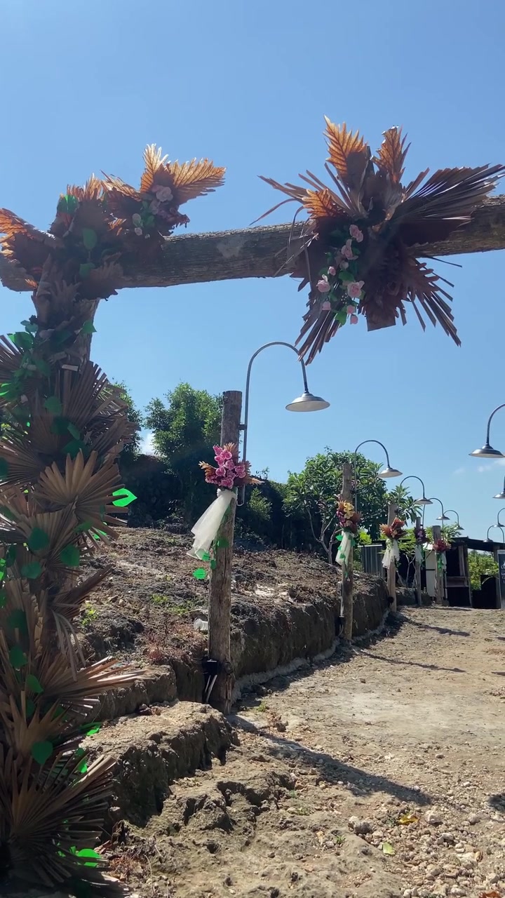 Arco esterno decorato e sentiero con fiori e lampioni.