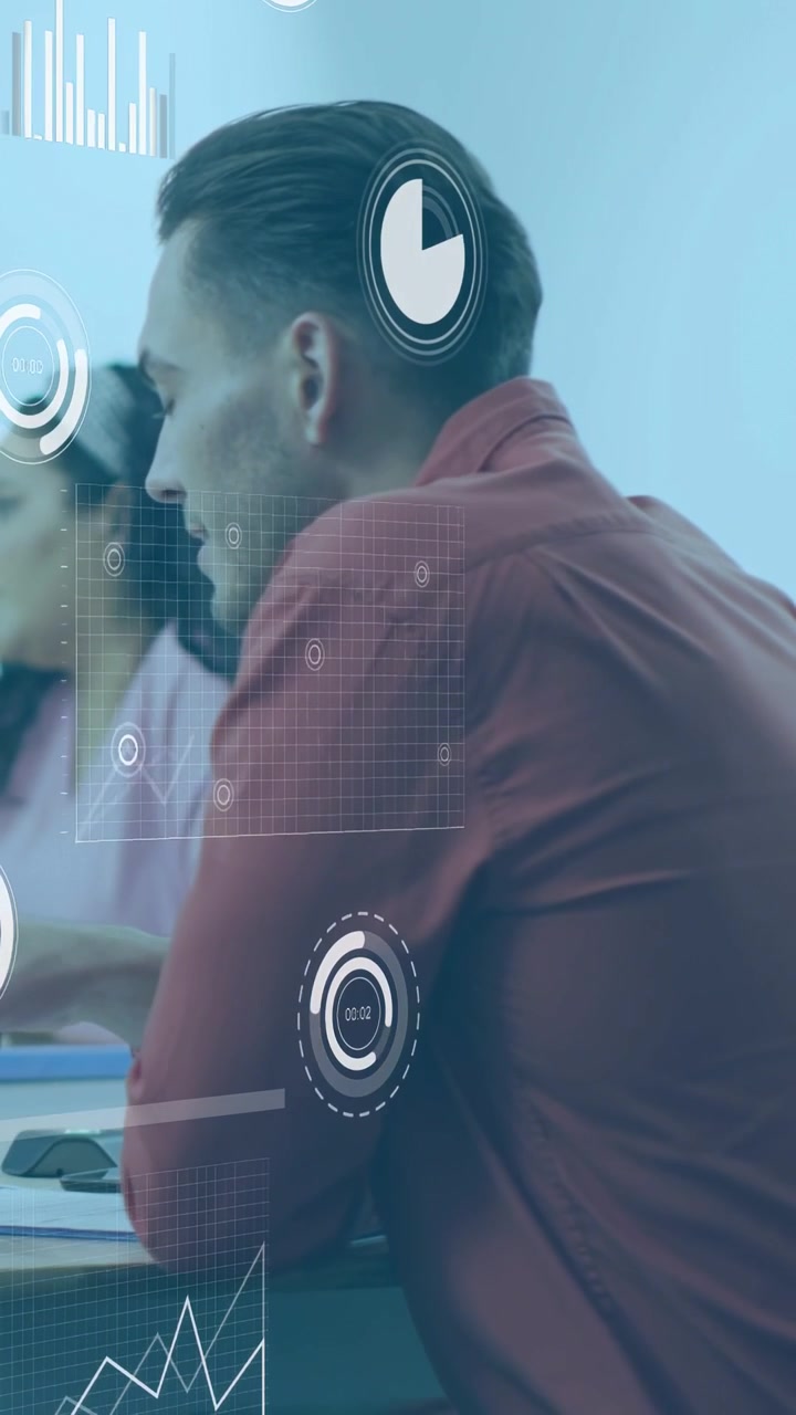 Vertical video: Man in red using mouse at desk animating bars, line, dials, reviewing business data