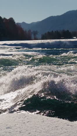 Rushing river water creates dynamic waves in winter landscape at mountain edge