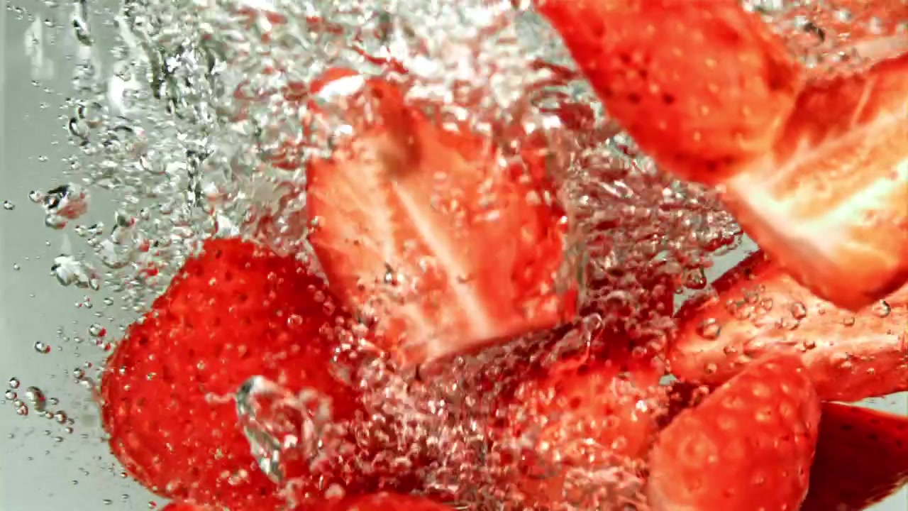 新鮮な赤いイチゴが泡を立てて水に飛び込む様子