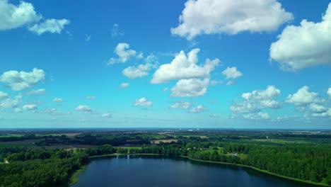 Aerial-captures-vast-lake-surrounded-by-lush-trees-on-a-sunny-day