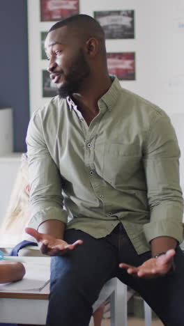 video of happy african american male teacher during lesson with class of diverse pupils