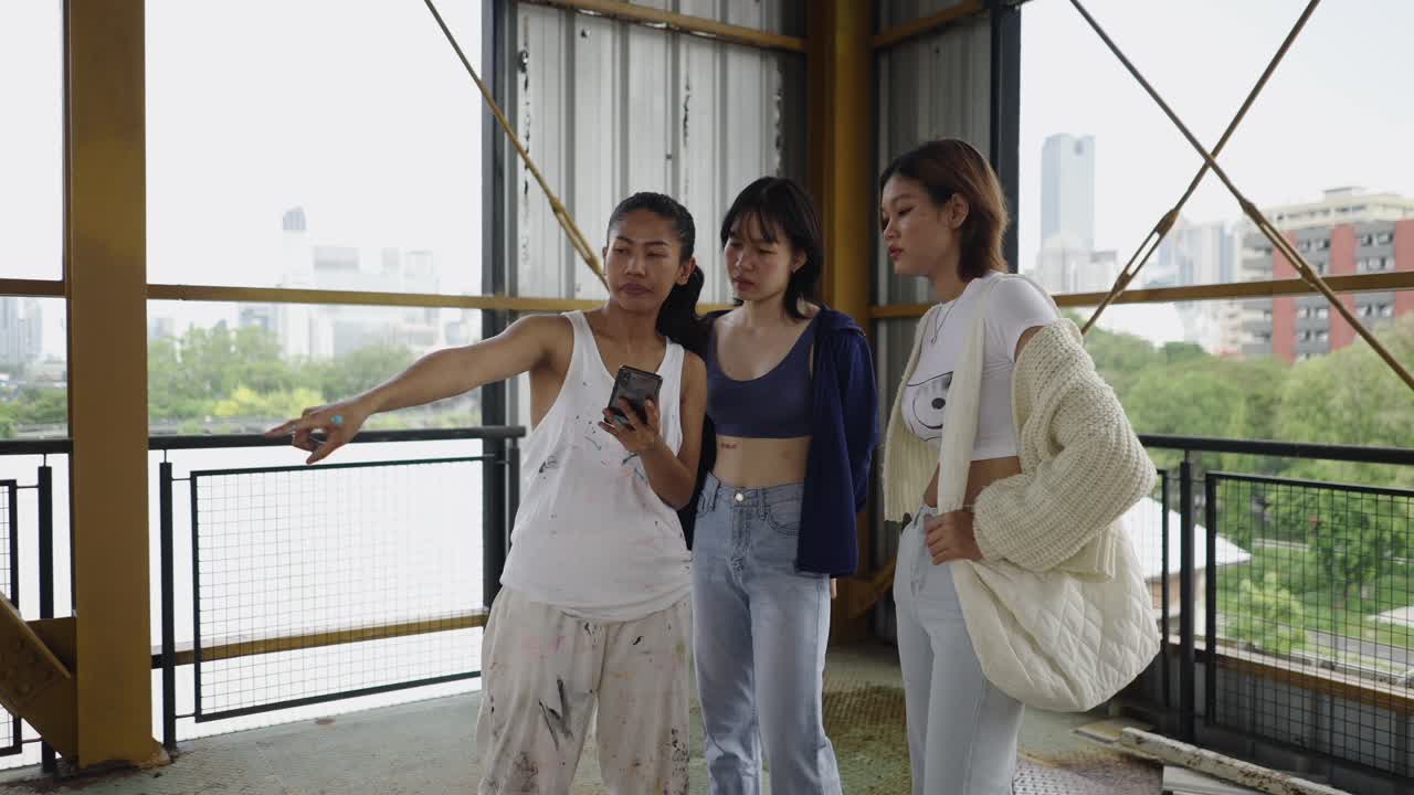 Three women looking at a smartphone in an urban environment