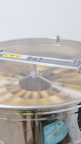 electric device for extracting honey from frames. centrifuge with frames rotating inside the metal barrel. vertical video