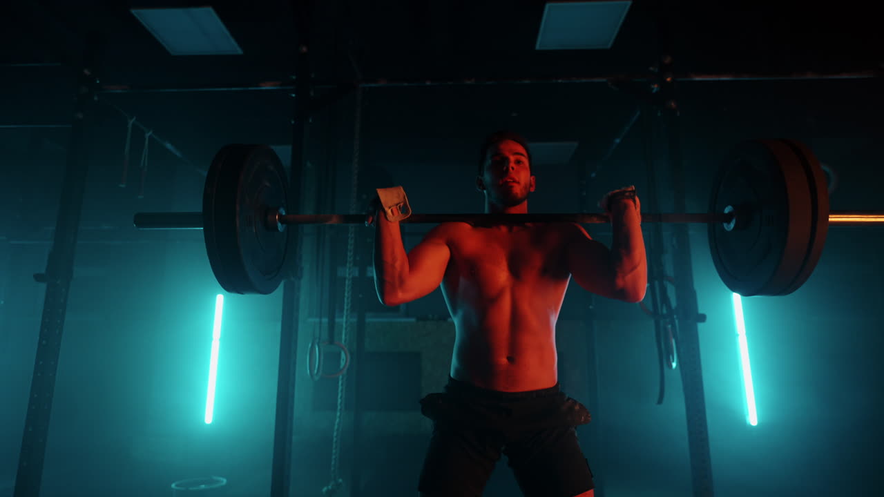 Athletic Shirtless Man Training Doing Power Strength and Endurance Exercises with Barbell. Workout in the Hardcore Gym in slow motion