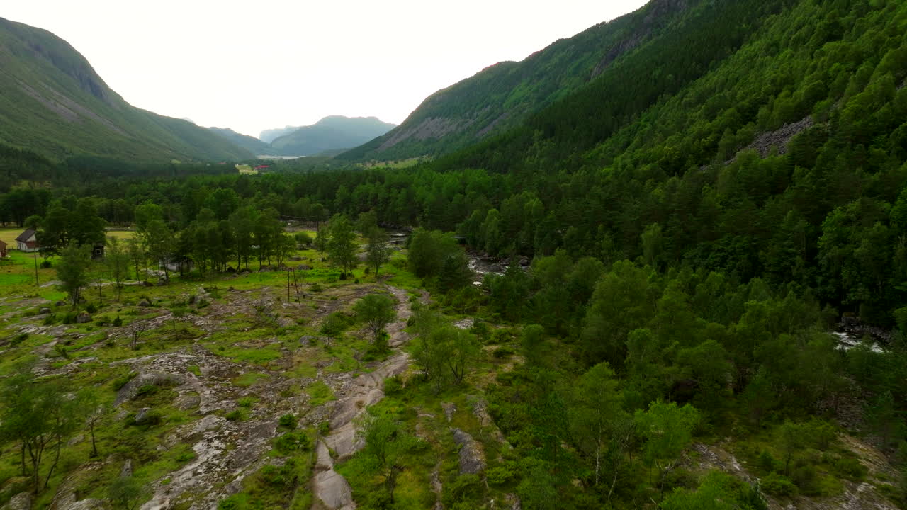 Southwest Norway hiking overview, green mountains and trail winding through valley, aerial dolly establish
