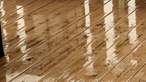 Lluvia-Cayendo-Sobre-Una-Cubierta-Pintada-De-Marrón-Claro-Con-Daños-Por-Agua,-Con-Algo-De-Reflexión