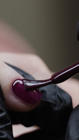 applying dark purple nail polish