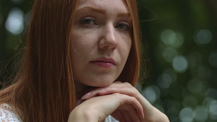 Portrait of red hair woman in summer park with serious face expression