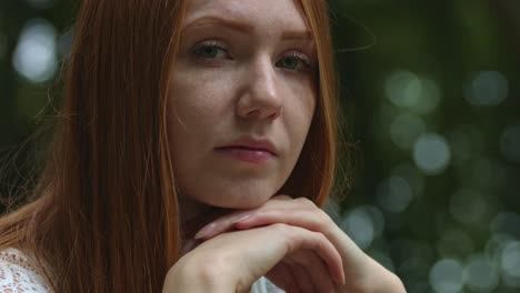 retrato de mujer pelirroja en el parque de verano con expresión de cara seria