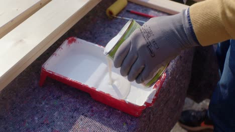 el trabajador vierte el esmalte interior en la bandeja de pintura
