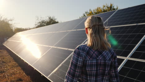 a woman walks along the solar panels of a small home solar power plant