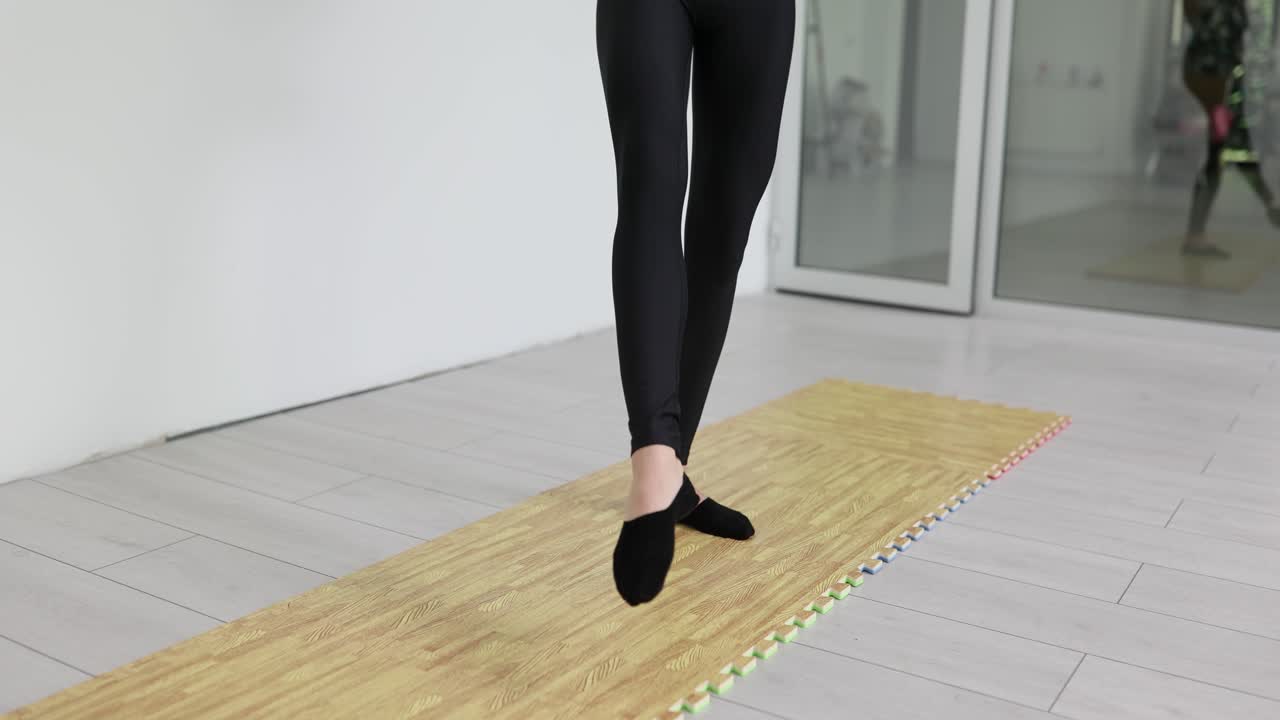 Female legs do warmup motions on domestic foam exercise mat