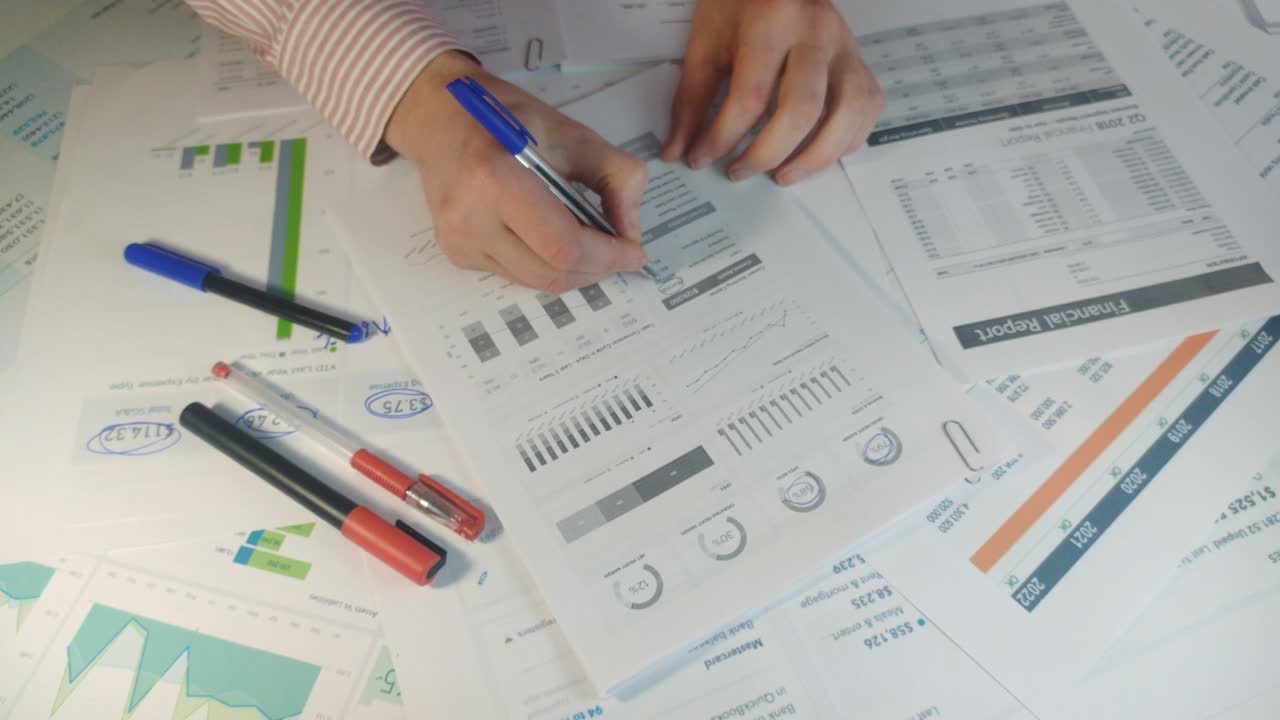 hombre de negocios con pluma en la mano examinando gráficos en documentos de primer plano vista superior