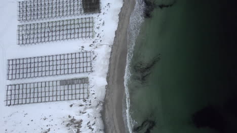 Wooden-dry-fish-racks-at-hovden-Beach-Norway-Bo-in-Vesteralen,-Bird-view-shot-4k