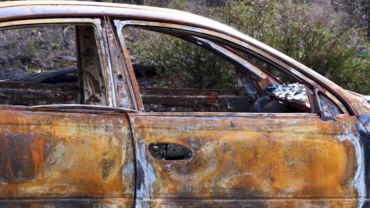 Close-up of a rusted, fire-damaged sedan abandoned in Goonoo Forest, New South Wales, Australia.