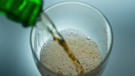 alcohol liquid jet bubbling into transparent glass top view. bottle pouring beer