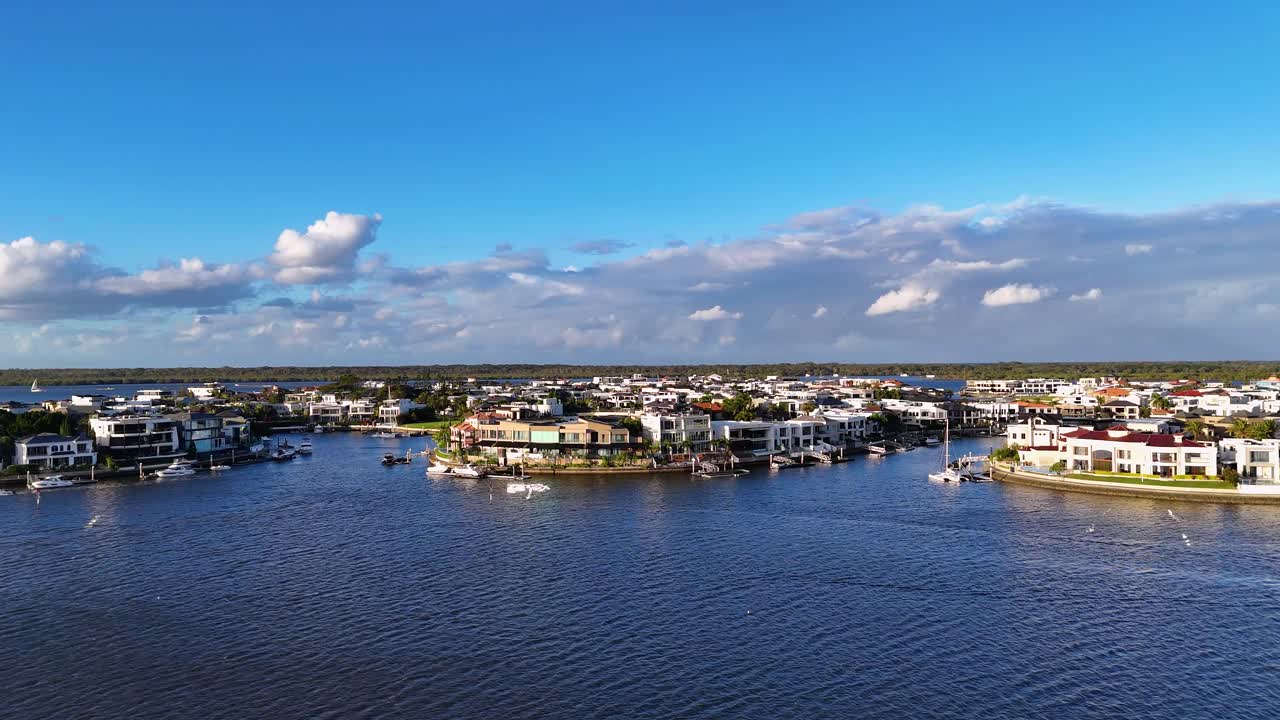 Drone footage captures luxurious waterfront homes and boats under clear skies on Australia's Gold Coast