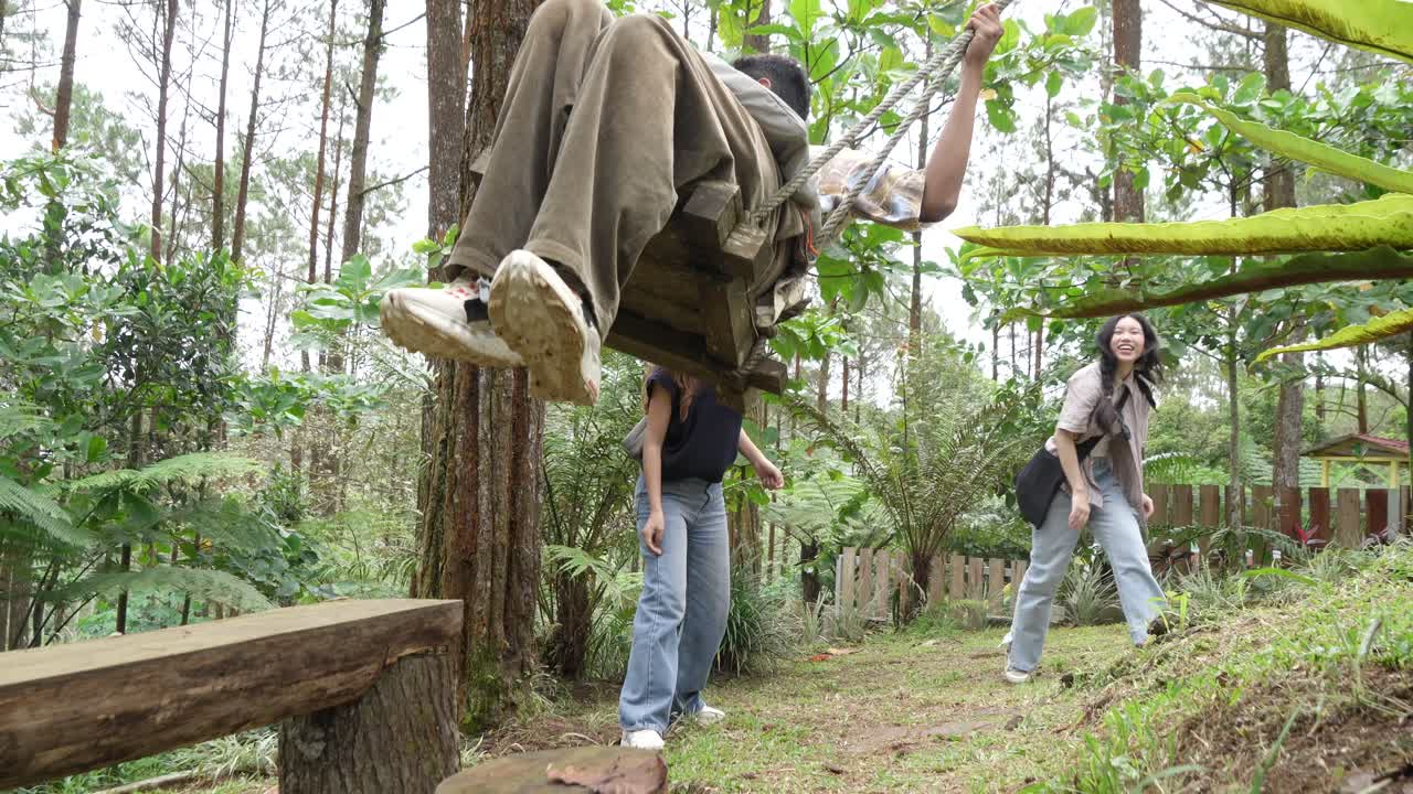 Indonesian Friends Playing on a Swing in Forest During Outdoor Travel Adventure