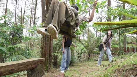 indonesian friends playing on a swing in forest during outdoor travel adventure