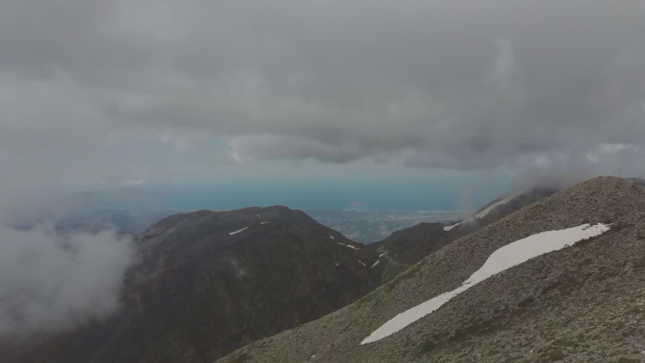 Aerial view of a hike girl that walks on a mountain peak during a foggy day. Hiker on the top of mountain and drone reveals the landscape. Travel and freedom concept in 4k. Side view