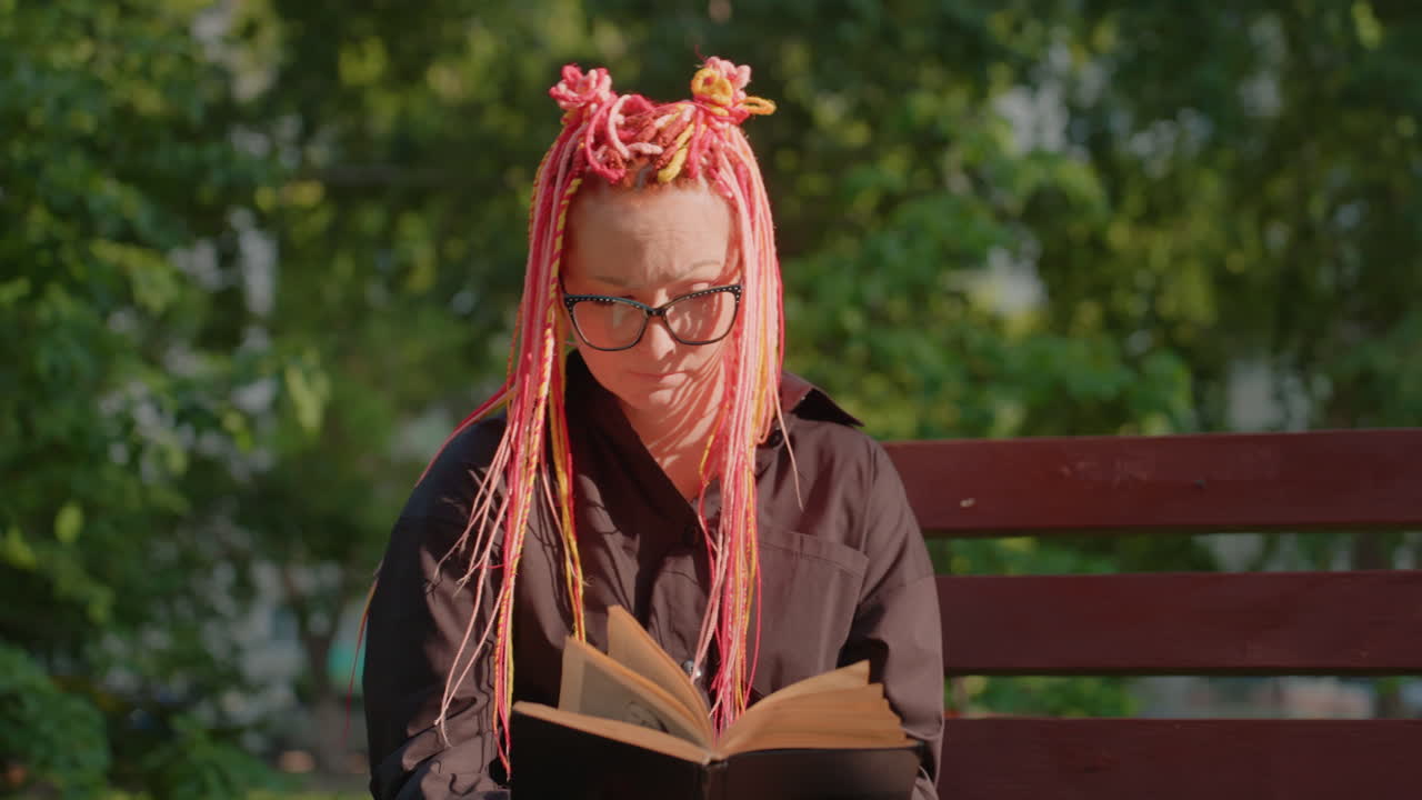 한 여성이 화창한 오후에 평화롭게 야외에서 독서를 즐기고 있어요. 고요한 여성이 햇볕이 잘 드는 야외 환경에서 평화롭게 앉아 책에 몰두하고 있네요.