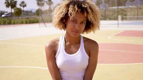 pretty young female athlete sits on basketball