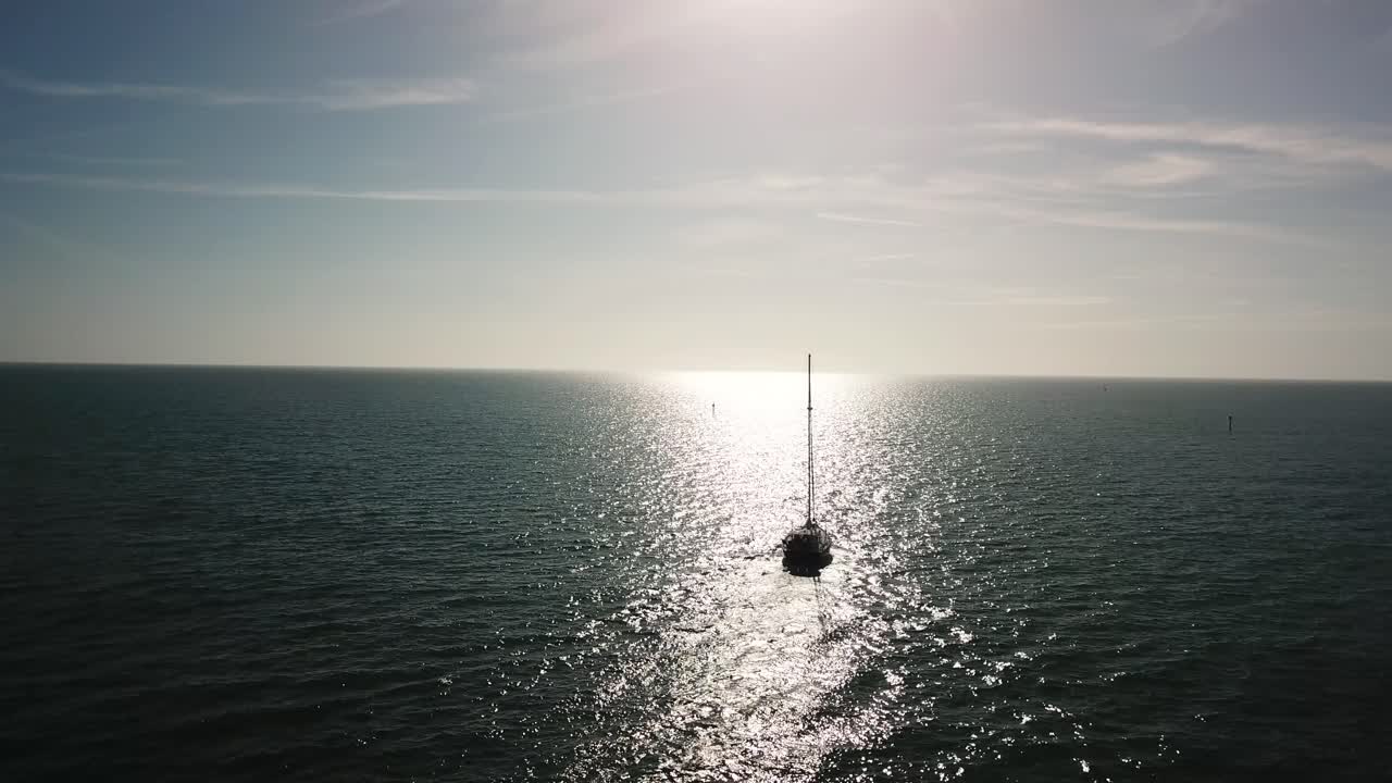 Sailboat on the Ocean with Sun Reflection
