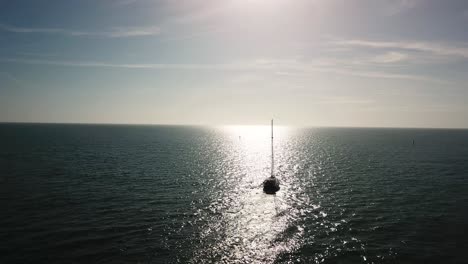 sailboat on the ocean with sun reflection