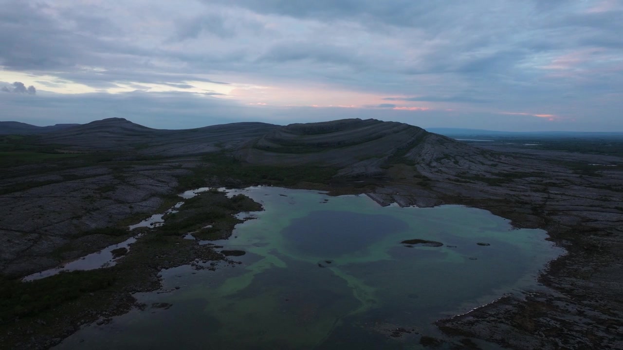 Kalksteinsformasjoner omgir rolige bassenger under en skumrende himmel i County Clare. Egnet for geologiske studier eller landskapsdokumentarer.