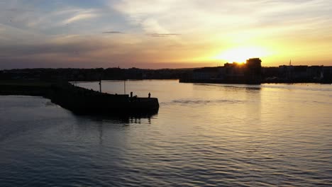 aerial view captures sunrise rays illuminating the sea from nimmo's pier entrance as seagulls glide by