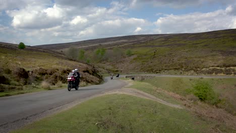 motorcyclists sweep through a sharp bend on a narrow moorland road