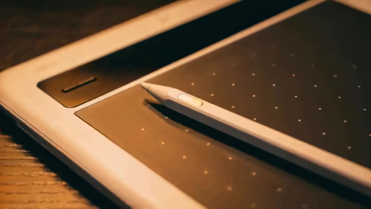 Moving camera framing digital stylus and graphics tablet on wooden desk, highlighting side button