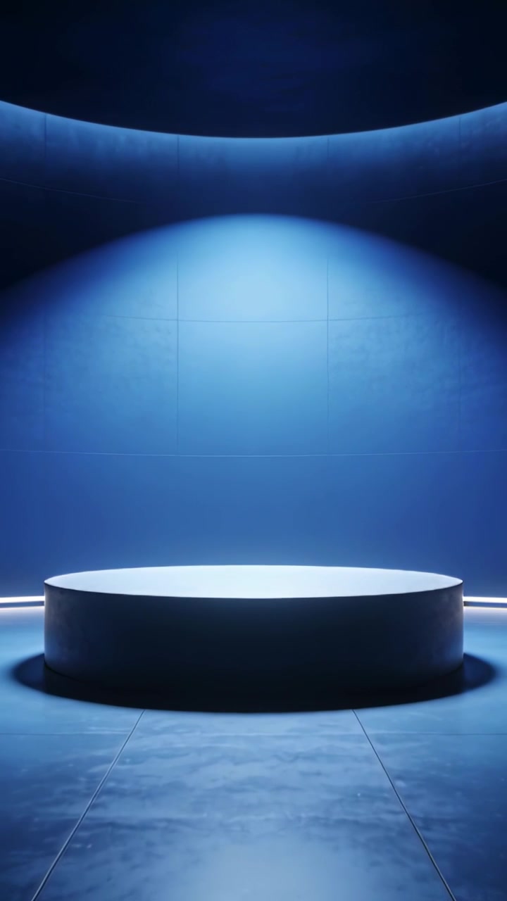 Vertical video: Camera zooming, revealing center pedestal under spotlight, LED rim on blue backdrop