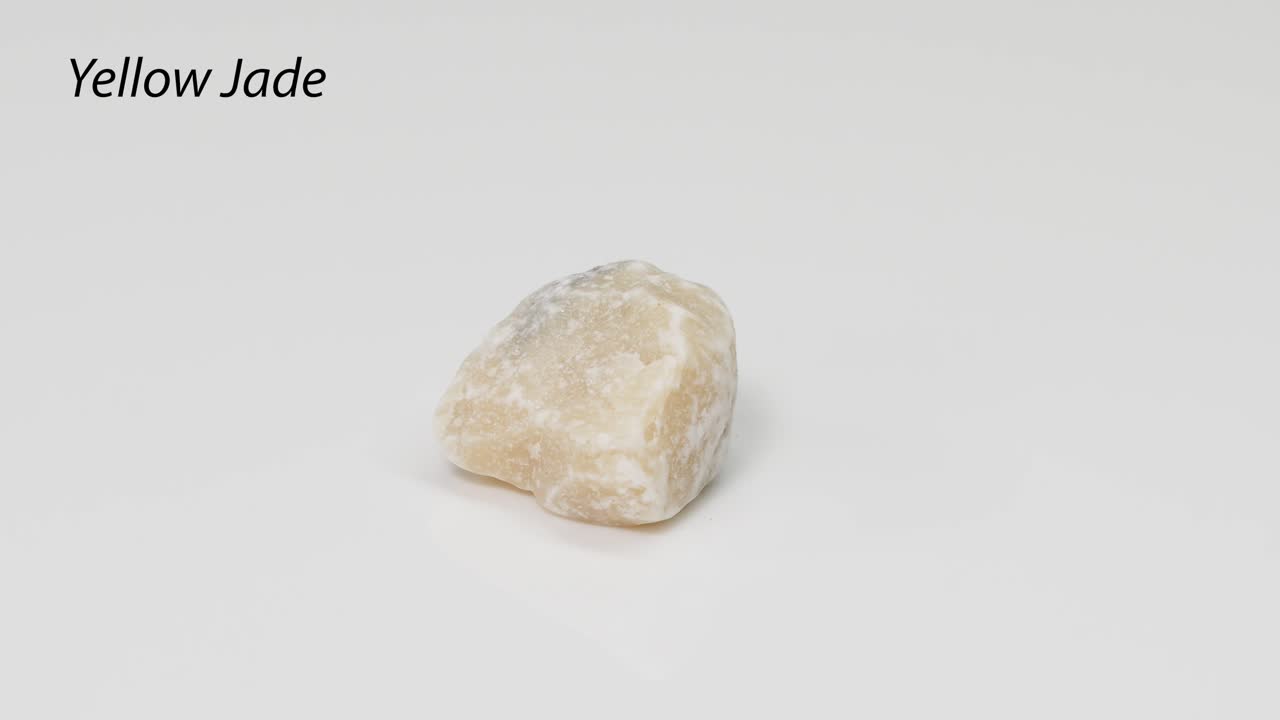 Yellow jade stone rotating on a white surface