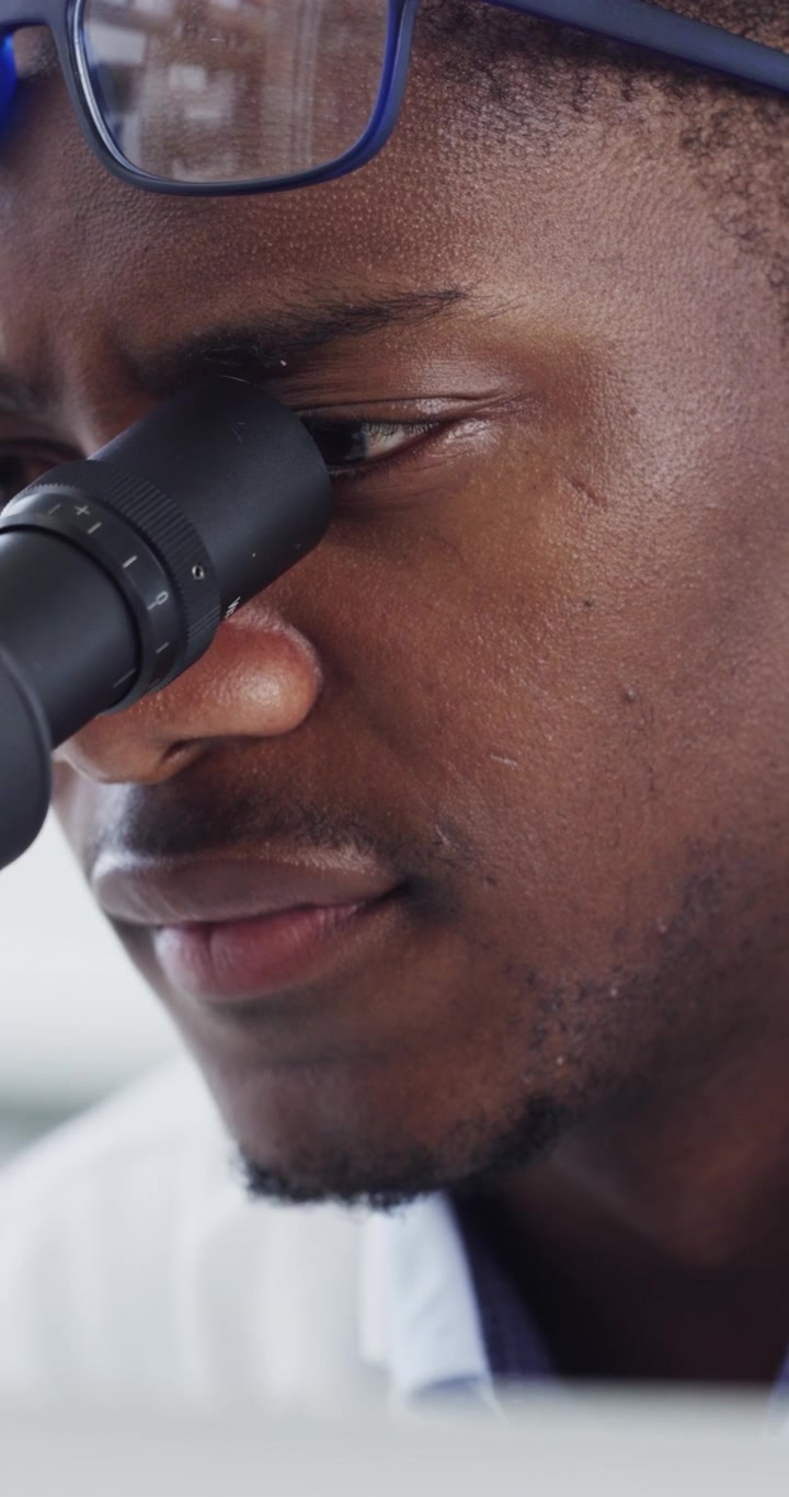 Scienziato che Regola gli Occhiali e Osserva al Microscopio in Laboratorio