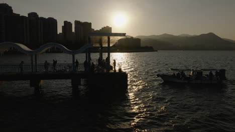 vista aérea de la silueta del barco en el muelle de la ciudad de hong kong con el horizonte de la metrópolis china en segundo plano.