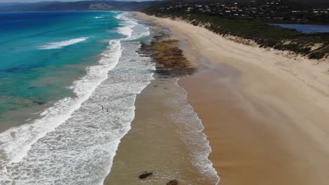 Aerial-view-over-waves-sweeping-over-a-tropical-beach-in-sunny-Australia