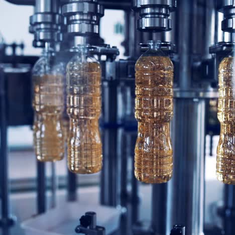 botellas de plástico con aceite que se mueven en círculo. equipos industriales que llenan el aceite de girasol en las botellas. producción de la fábrica de aceite de cocina.
