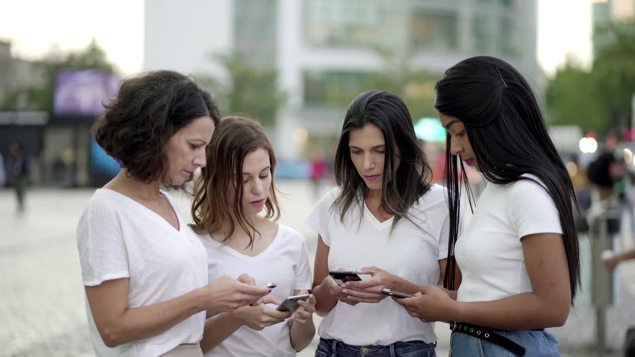 mujeres jóvenes concentradas usando teléfonos modernos en la calle