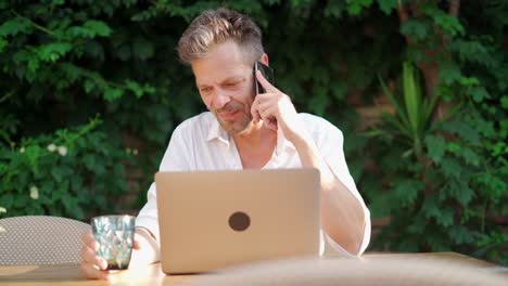 Businessman-drinking-beverage-and-talking-on-cellphone-in-street-restaurant