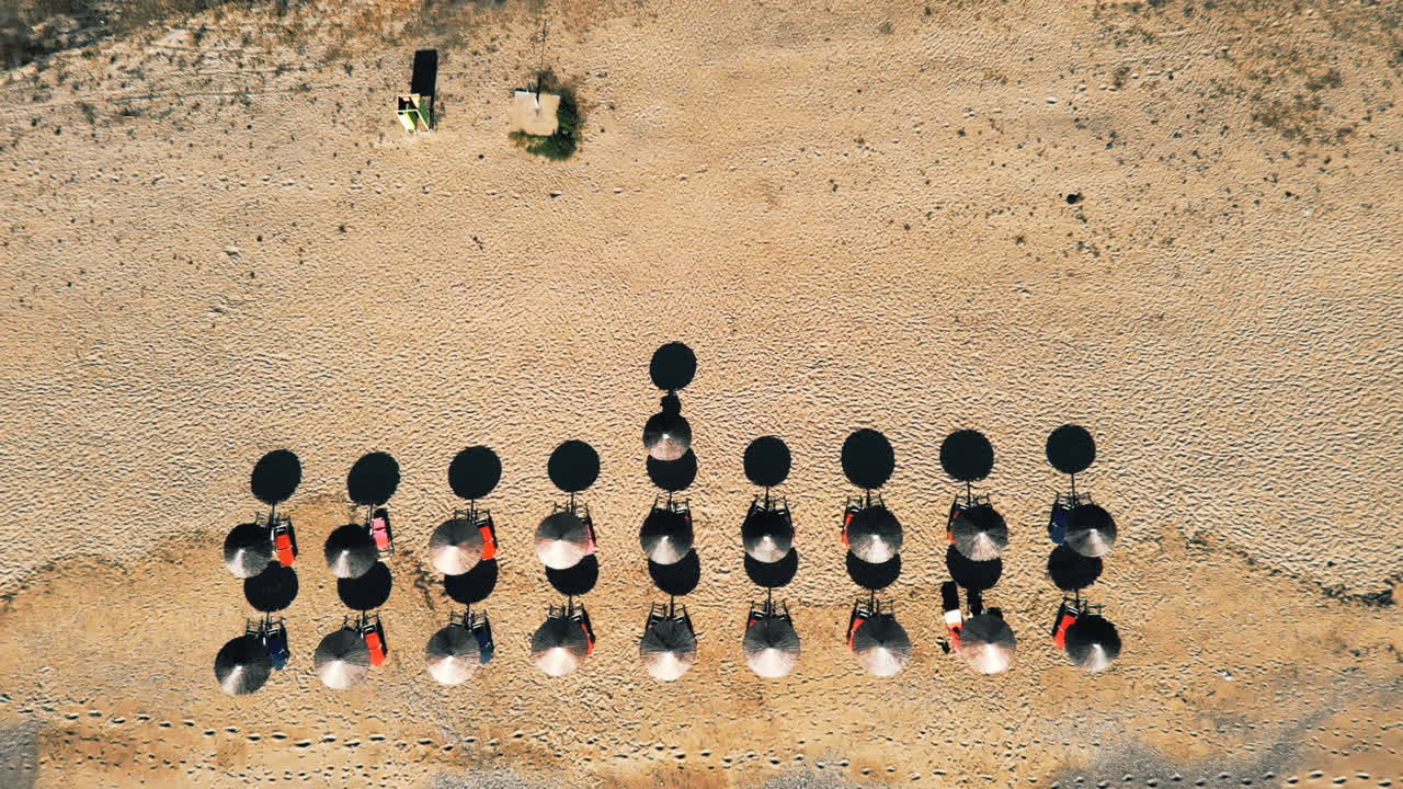 Waves of the sea and a beach with umbrellas and sunbeds. Foam. Top view. Sprovalta, Greece