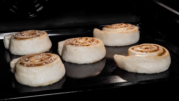 Timelapse - five cinnamon buns baking and rising in electric oven at home