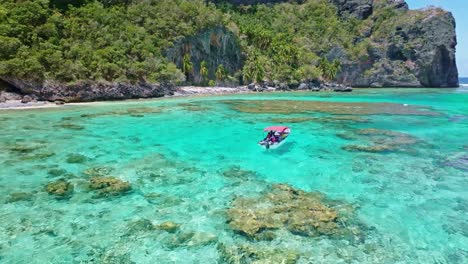 Drone-view-of-tourists-sailing-by-boat-on-Fronton-beach-in-Las-Galeras-Samana,-Dominian-Republic