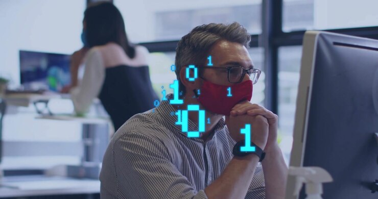 Seated man red mask glasses reacting to binary overlay in office clasping hands analyzing tech data