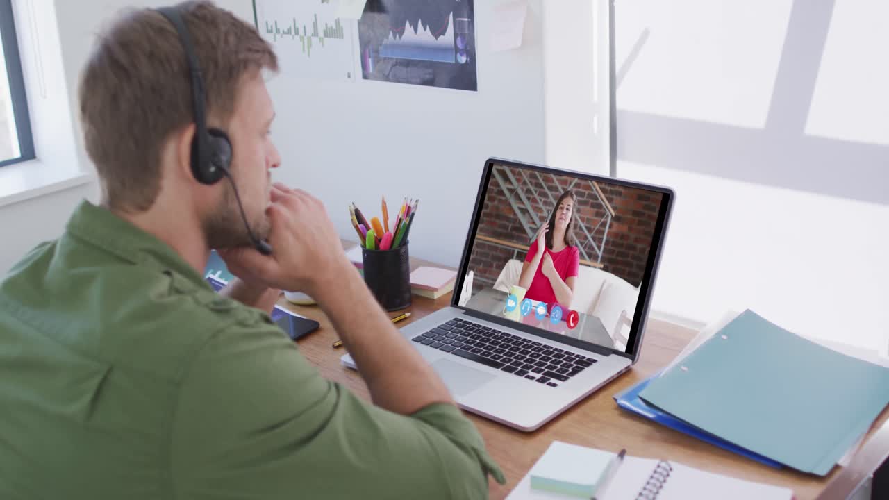 Kaukasisk mand bruger bærbar computer og telefonheadset på videoopkald med en kvindelig kollega.