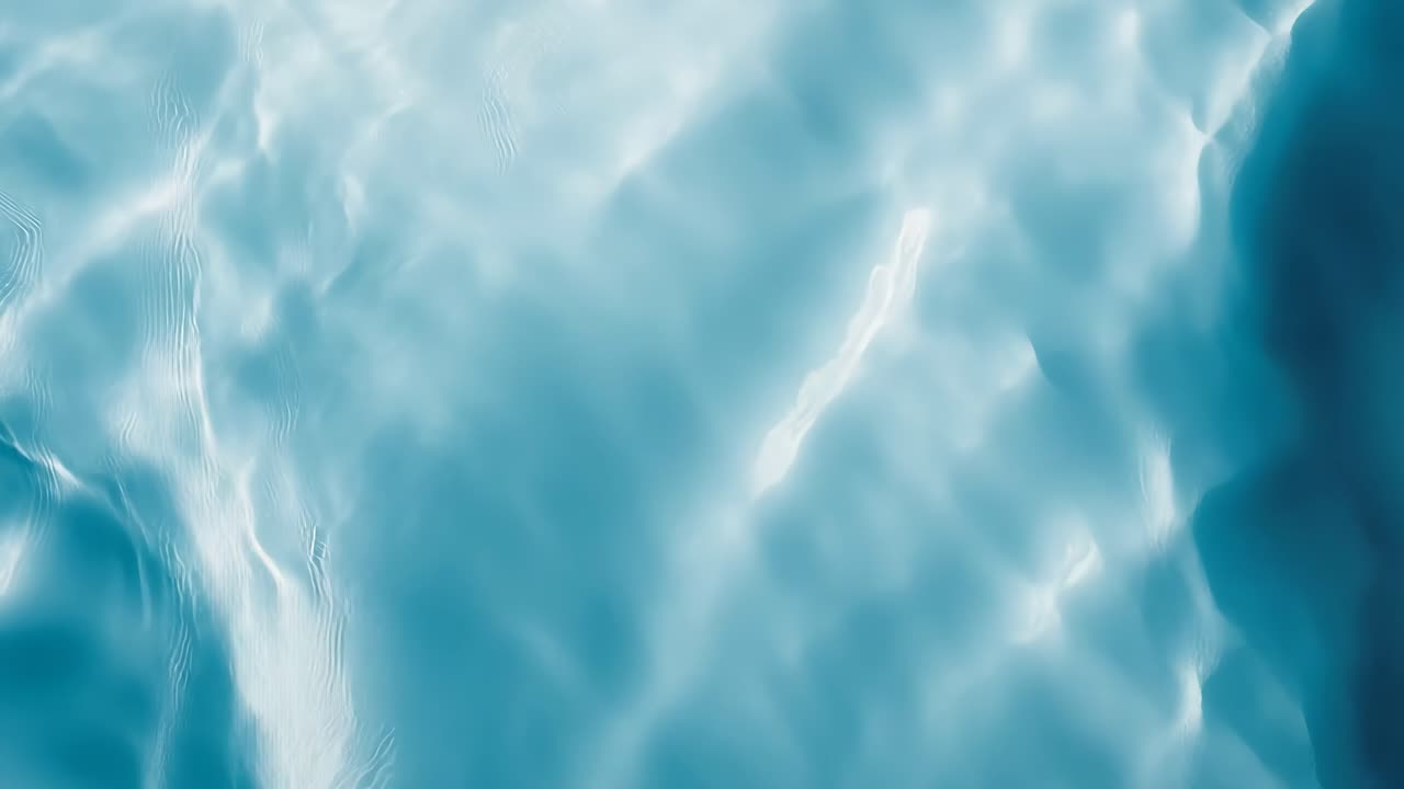 Aerial view of serene, rippling blue water, capturing the fluid motion and light reflections