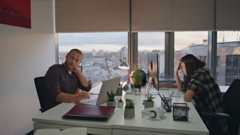 tired colleagues working office sunset view. exhausted people watching computers