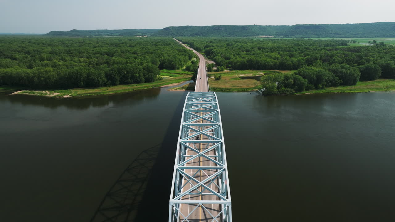 Sorvolando il ponte Wabasha-Nelson sul fiume Mississippi con una lussureggiante foresta verde in lontananza.